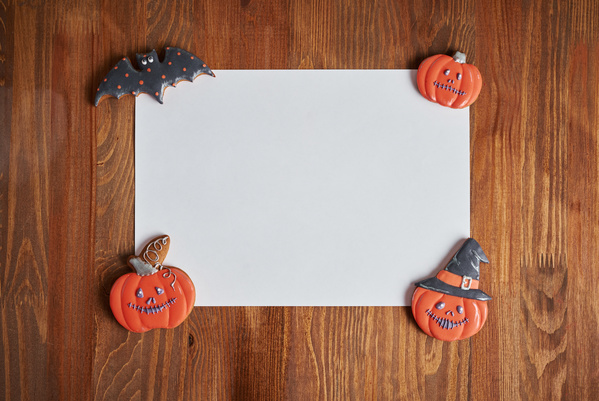 Various Black And Orange Halloween Cookies Are Placed on Corners of Sheet of Paper
